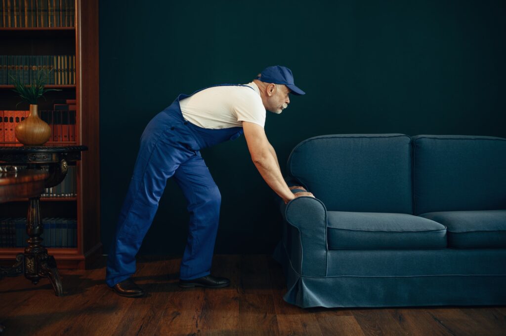 Elderly cargo man in uniform moves sofa
